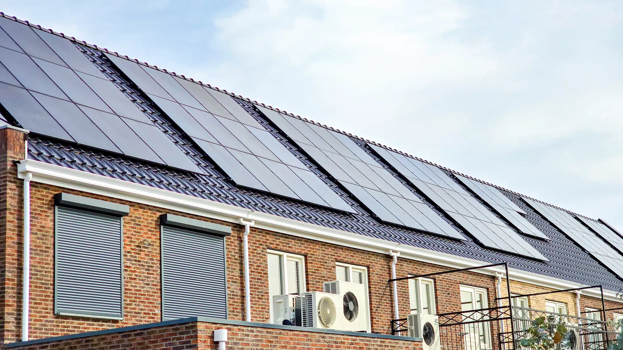 Woning met zonnepanelen op het dak en warmtepompunits aan de gevel